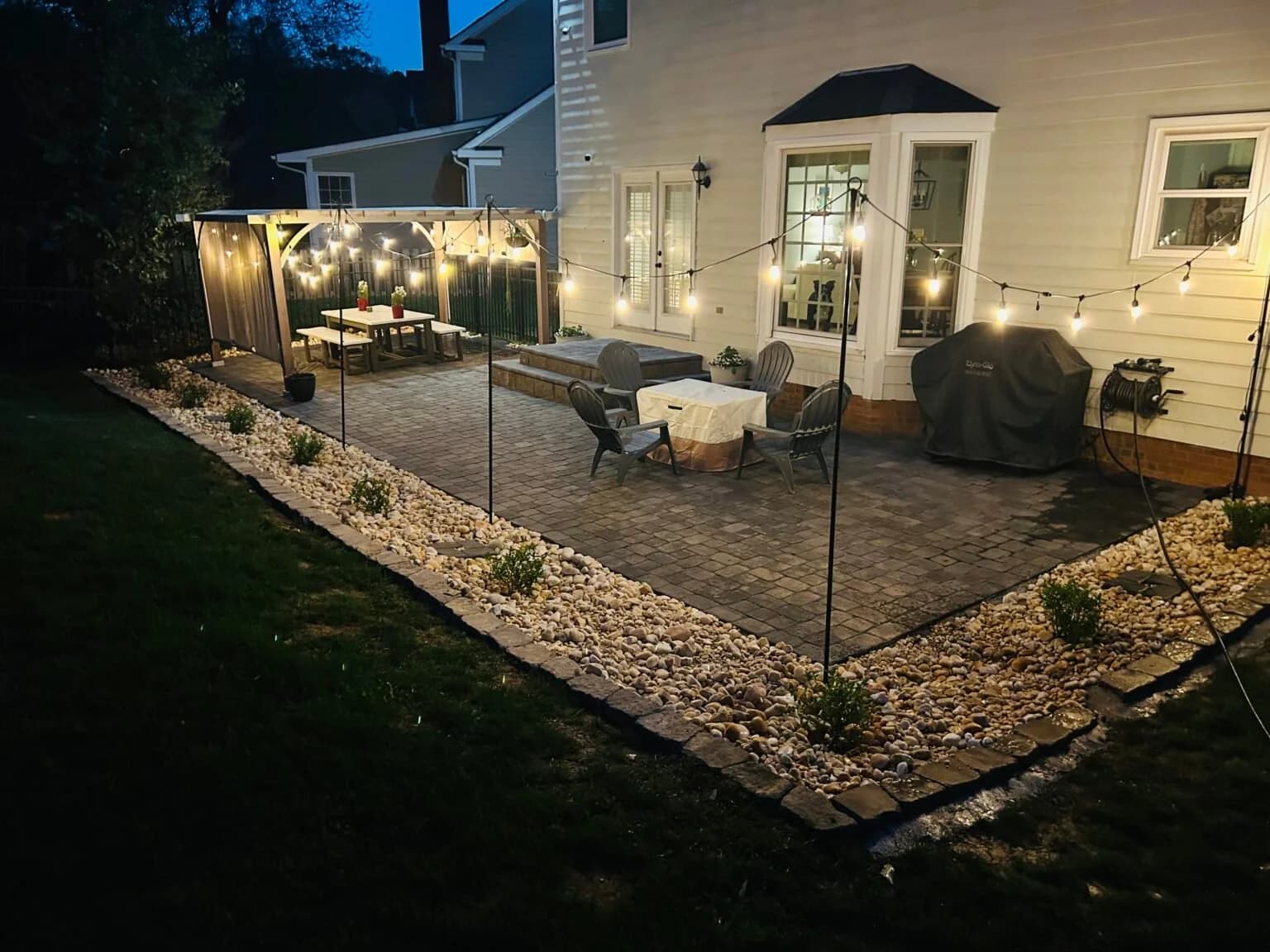 Urban pergola and patio at dusk with a furnished outdoor dining area