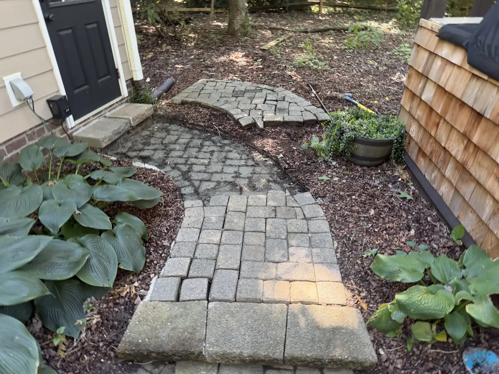 Existing curved paver path with a section lifted during renovation