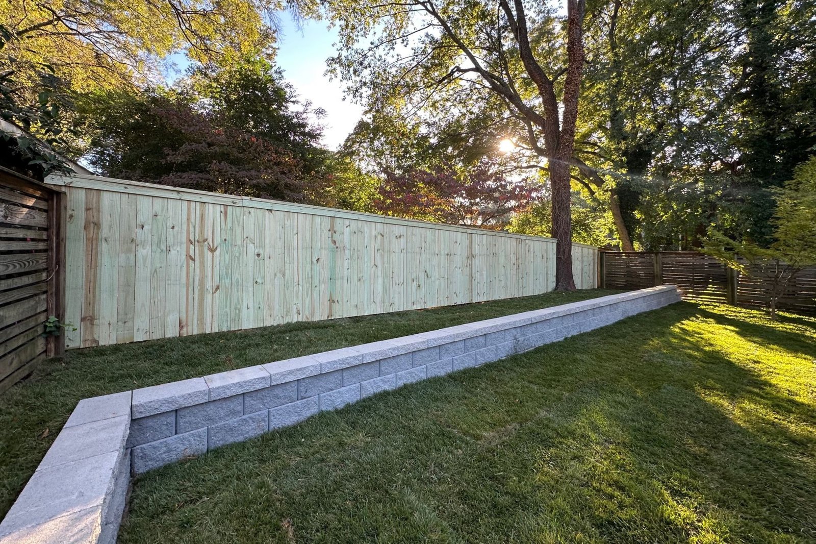 Completed Suburban Sanctuary retaining wall, fence, and lawn project