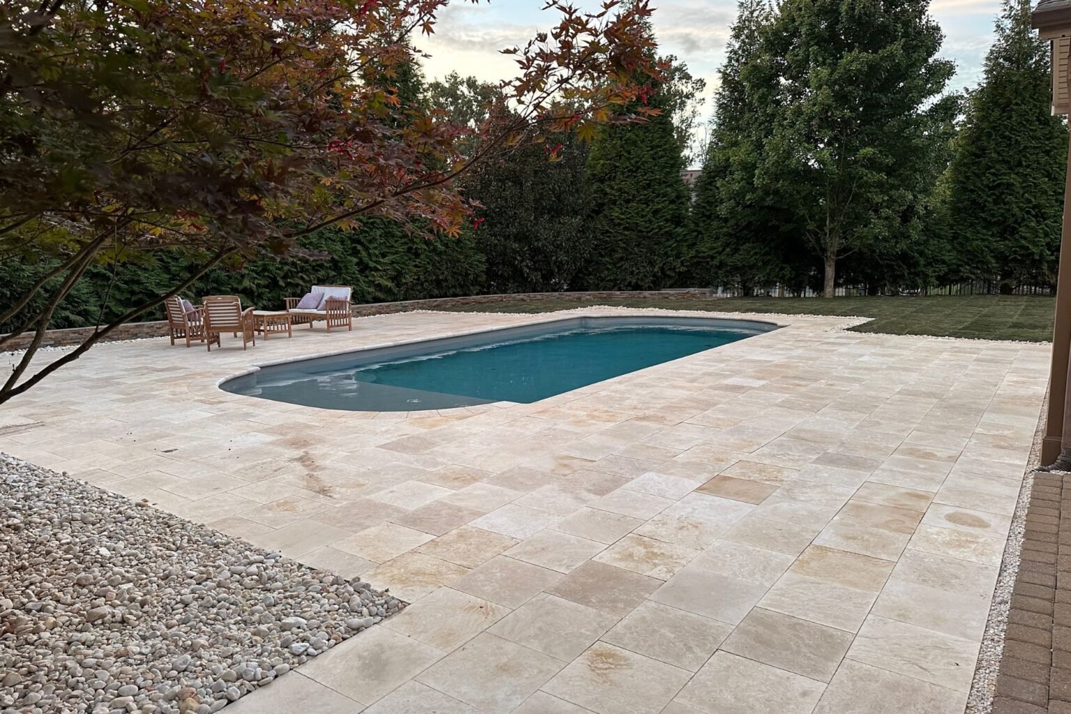 Completed paver patio surrounding the Poolside Paradise pool with lawn and trees