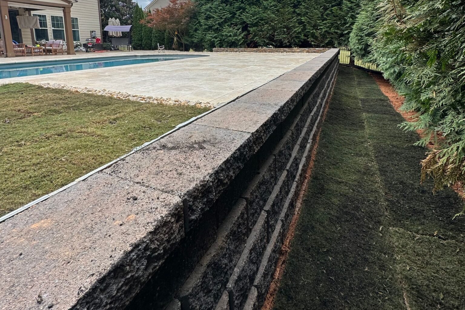 Dark block retaining wall beside the Poolside Paradise lawn and patio