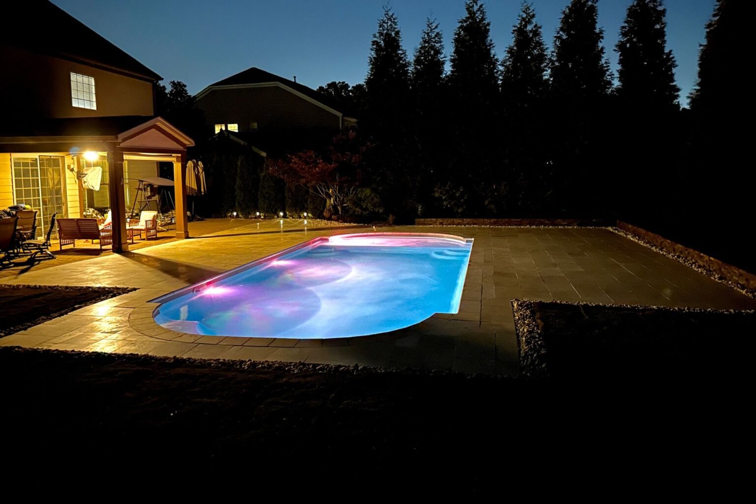 Poolside Paradise pool and paver patio illuminated at night