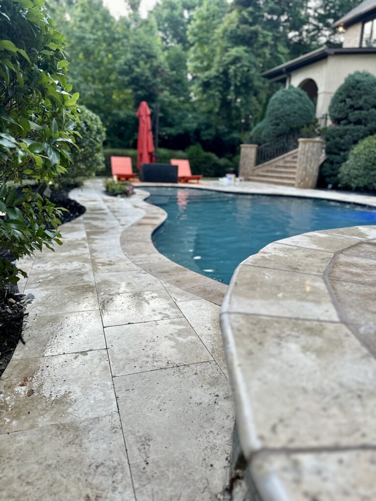 Finished travertine poolside surface beside the water