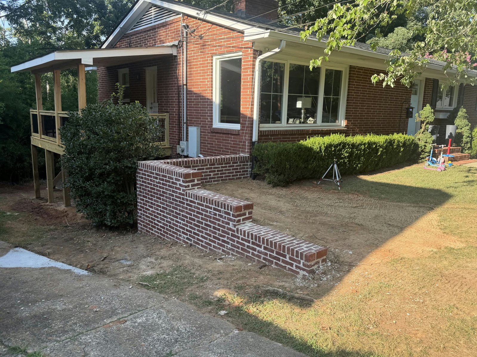 Finished red brick retaining wall beside a red brick house in Charlotte