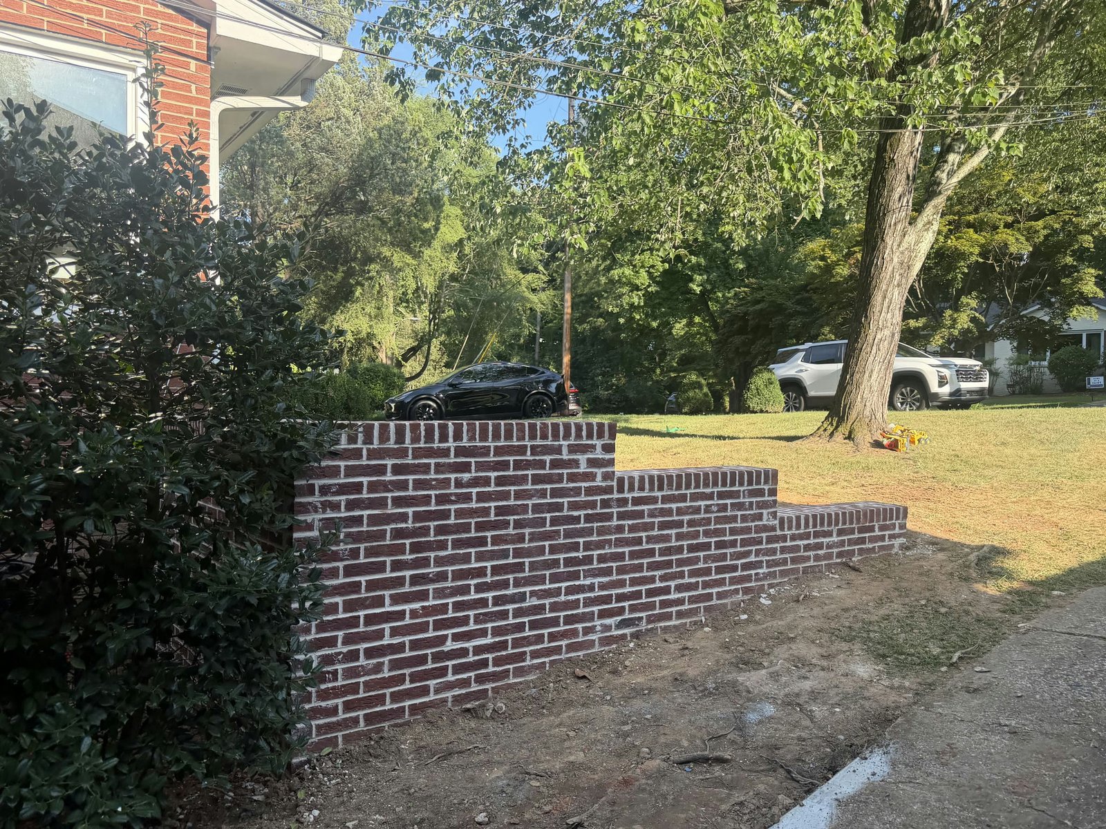 Side view of the finished red brick retaining wall beside the brick house