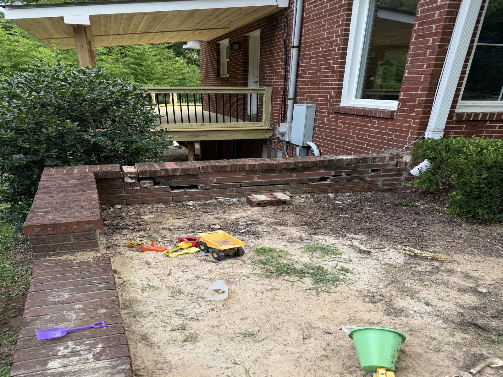 Old red brick retaining wall before removal beside the brick house