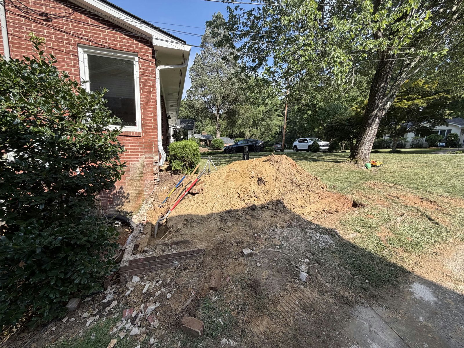 Open retaining wall work area beside the red brick house during replacement