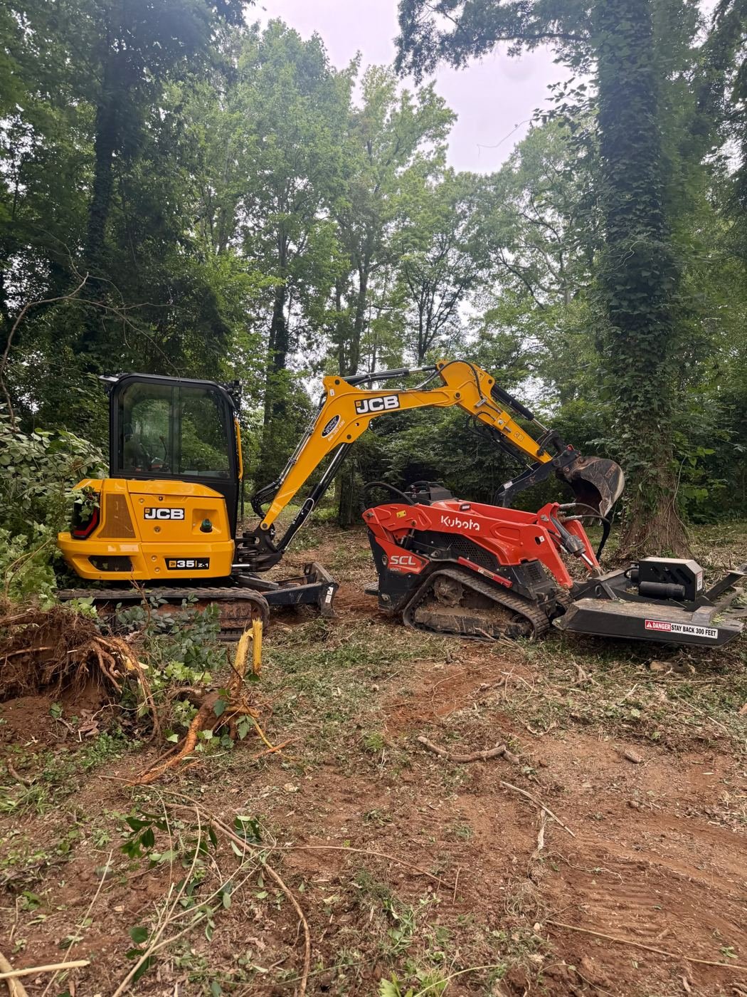 Mini excavator and compact tracked loader with brush-cutting attachment at the Mint Hill job
