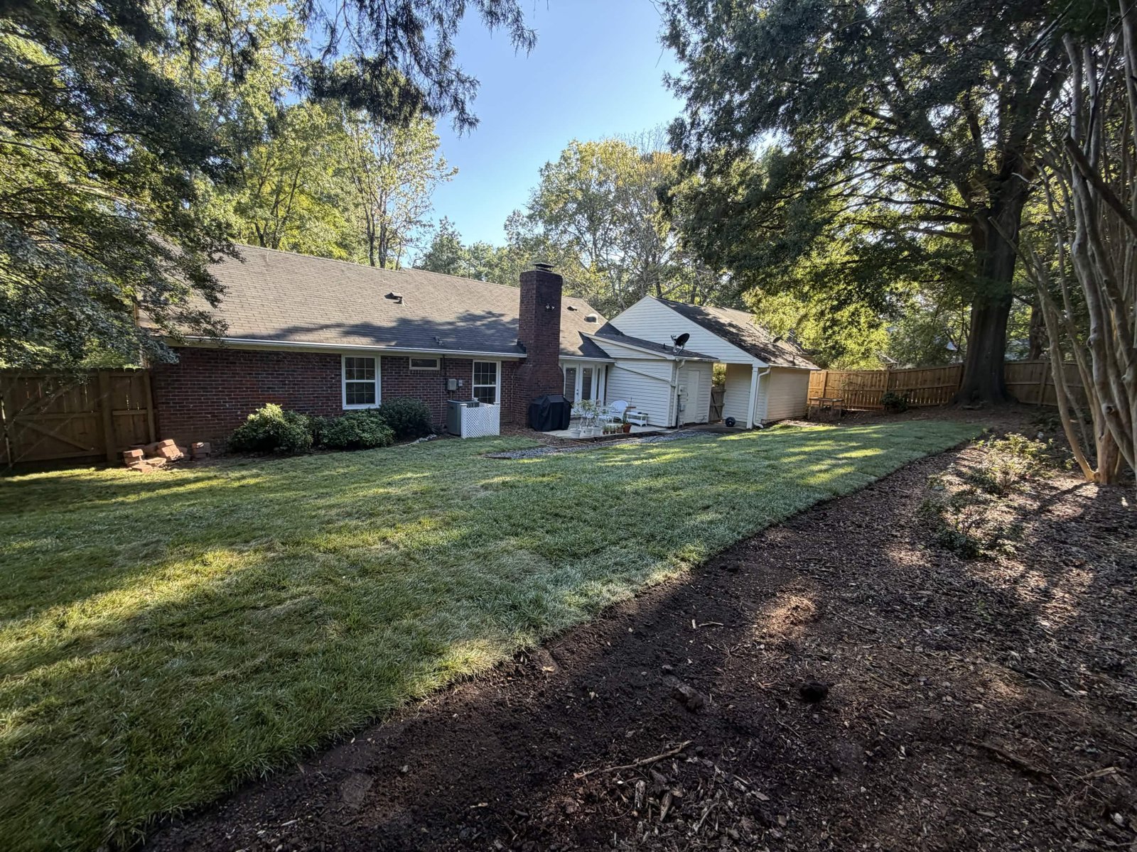 Wide view of the backyard after timber removal, grading and sod installation