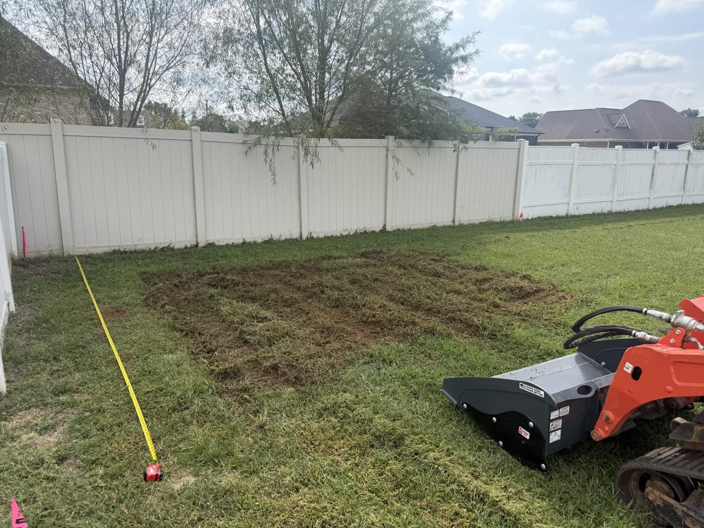Measuring tape and disturbed turf where the gravel pad will be installed