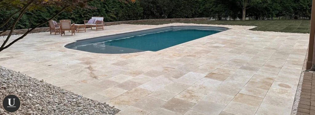 Light stone paving around a backyard swimming pool with outdoor seating